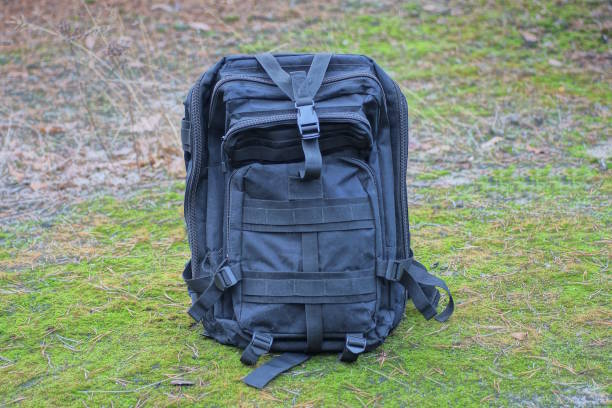 istock one brack army backpack stands on gray ground and green moss 1826503403