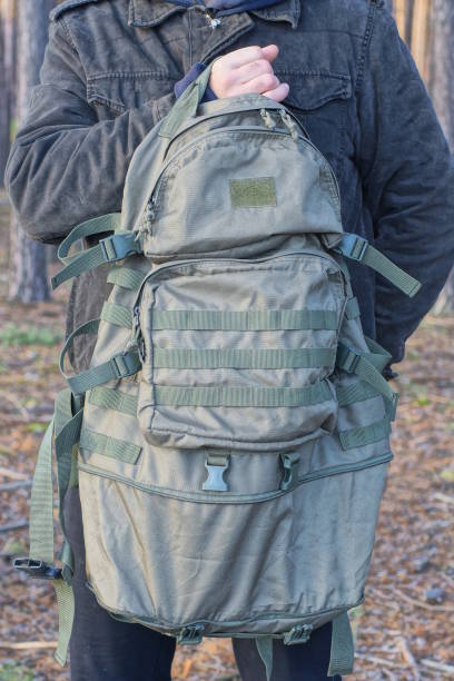 istock one man in gray clothes holds a large green army backpack in his hand 1826505591