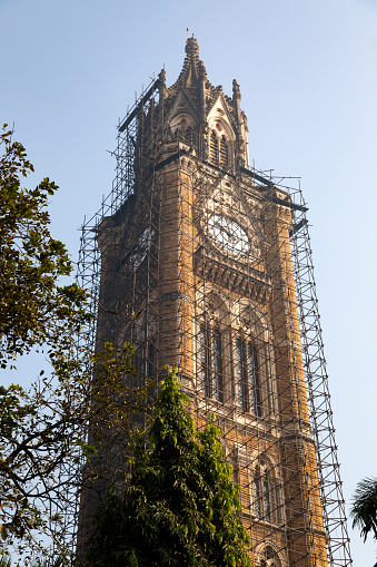 This image features the Rajabai Clock Tower, a prominent landmark in Mumbai, known for its striking Gothic Revival architecture. Located within the University of Mumbai campus, the tower stands at an impressive height, dominating the skyline. The photograph captures the tower's intricate stonework, spires, and the distinctive clock face, which is a notable feature of this historical structure. Built in the late 19th century, the Rajabai Clock Tower is not only a functional timepiece but also a symbol of Mumbai's rich architectural heritage. The image aims to highlight the tower's elegance and historical significance, portraying it as a testament to the city's colonial past and its continuing legacy in the present.
