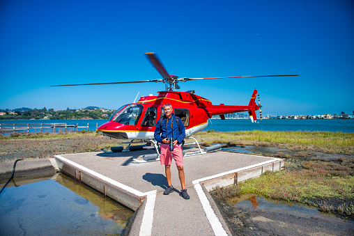 Happy tourist in front of a helicopter