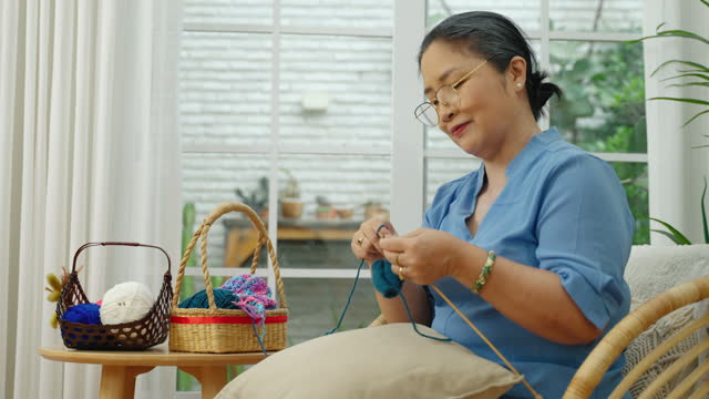 elderly Asian woman spends her free time crocheting as a hobby.
