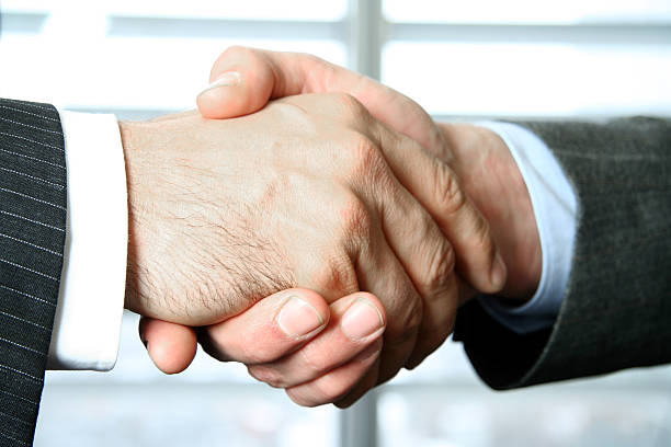 Businessmen greeting each other with a firm handshake stock photo