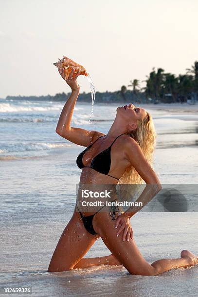 Mujer Vertiendo Agua De Carcasa Foto de stock y más banco de imágenes de Adulto - Adulto, Arrodillarse, Biquini