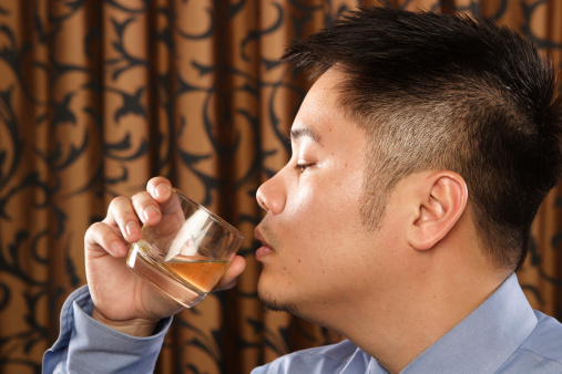 A man preparing to drink a  whiskey