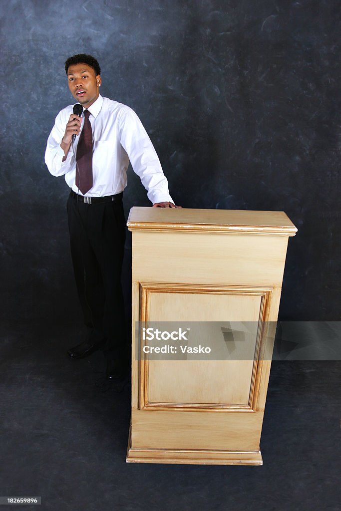 Public Speaking Picture of a young black male speaking from behind a podium. Adult Stock Photo
