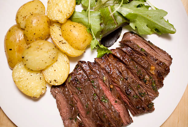 Marinated skirt steak "marinated skirt steak, grilled medium rare with roasted yukon gold potatoes and a small baby greens salad" flank steak stock pictures, royalty-free photos & images