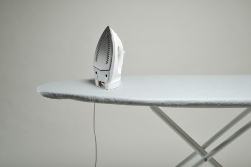 Ironing board and iron on a grey background. More iron...