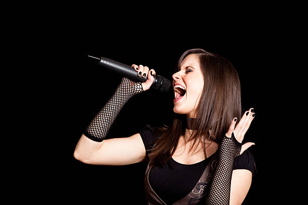 istock Happy Rocker Girl Singing into Microphone on Black Background 182660865