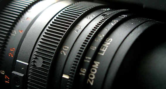 Camera lens with light and lens flare, close-up. Selective focus