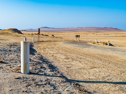 Stunning dirt road marked with white stakes, crossing the desert in Paracas National Reserve, Peru