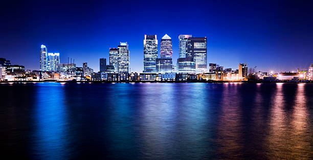 Canary Wharf London City Skyline UK Panoramic view of the illuminated Canary Wharf business area of London at twilight. Clear blue sky and reflection in the River Thames. canary wharf photos stock pictures, royalty-free photos & images