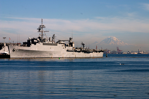 Warship moored alongside a pier at the Port of Seattle.  Mount Rainier is in the distance.