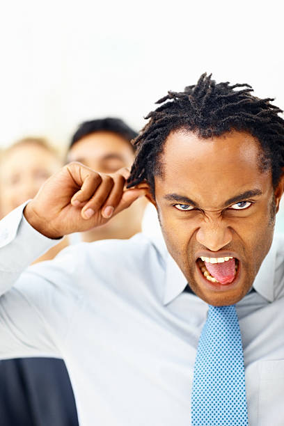 istock Funny businessman making a face with colleagues in the background 182661173