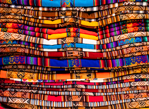 Stack of multicolored andean textile and fabrics in Pisac traditional market, Peru
