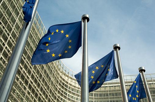 EU flags outside the European Commission Brussels Belgium. The European Commission (EC) is the executive body of the European Union responsible for proposing legislation, implementing decisions, upholding the EU treaties and managing the day-to-day business of the EU