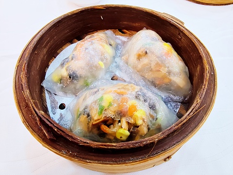 Dumplings (varenyky) with tasty filling on skimmer over pot indoors, closeup