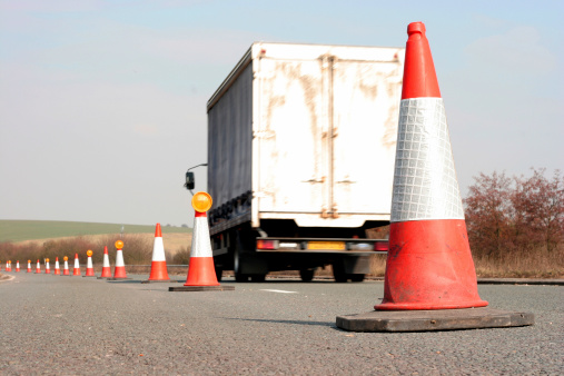 A shot of a white truck passing traffic cones on a highway