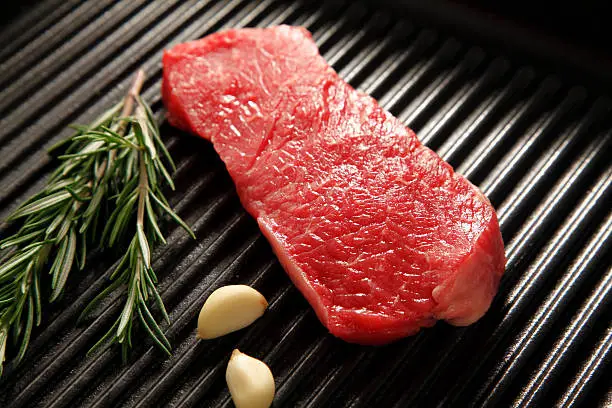 "Ready-to-eat steak.Name:New York steak or rump steak. Served in a steak pan.Typical aroma side dishes such as garlic and rosemary. The focus is on the front, right third of the image. Bon appetit!"
