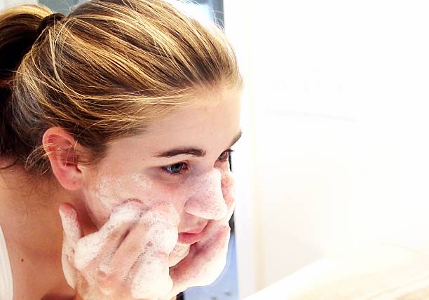A teenage blonde girl washing her face stock photo