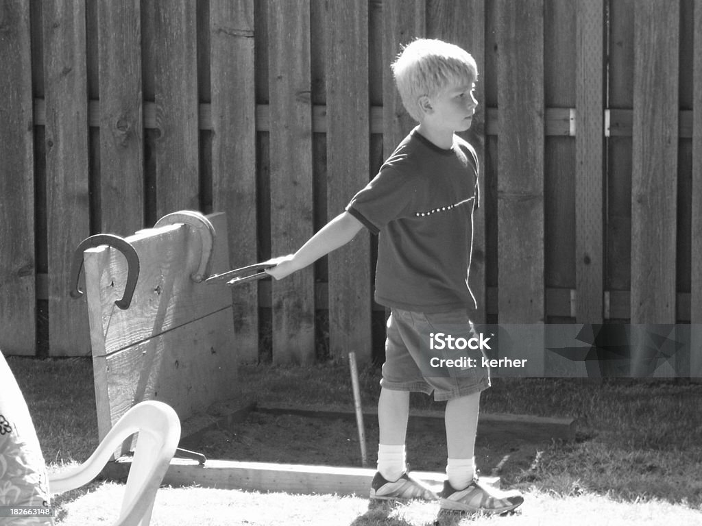 Ragazzo suona Lancio dei ferri di cavallo - Foto stock royalty-free di Ferro di cavallo - Accessorio per animali