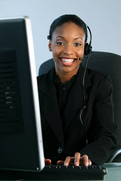 Help Desk Big Smile young woman (early twenties) wearing a headset and working on a computer - shot in studio modeldl stock pictures, royalty-free photos & images