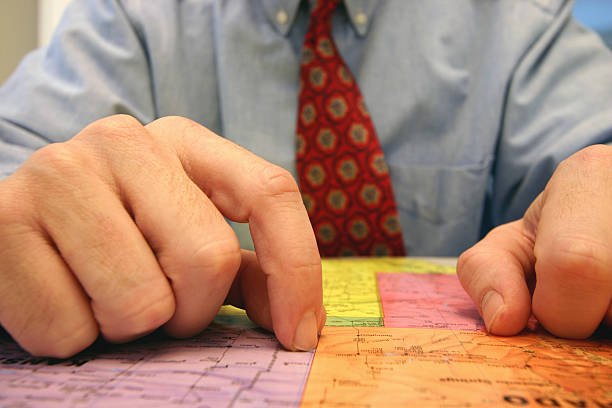 Business man in red tie analyzing maps stock photo