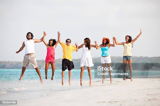 Foto de Grupo De Jovens Pulando Em Uma Praia Tropical e mais fotos de stock de 18-19 Anos - 18-19 Anos, 20 Anos, 20-24 Anos