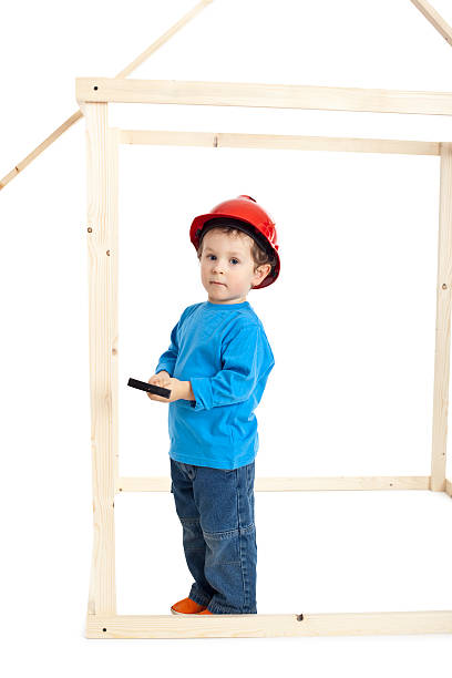 small boy building a wooden house isolated on white