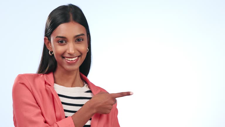 Pointing, smile and young woman in studio by mockup for marketing, promotion or advertising. Happy, portrait and Indian female model with presentation hand gesture by white background with mock up.