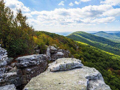 The untamed beauty of the wilderness reveals itself, showcasing wooded mountains against a backdrop of rocks in the foreground along the Big Schloss via Wolf Gap Trail, marking the border between West Virginia and Virginia. This captivating vista captures the rugged charm of the mountains amidst this trail's scenic landscape.