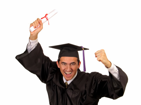 A very happy and active young man dressed in a collegiate cap and gown holding a diploma roll above his head (isolated on a white background)