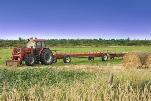 Farm tractor with flatbed trailor in a field.