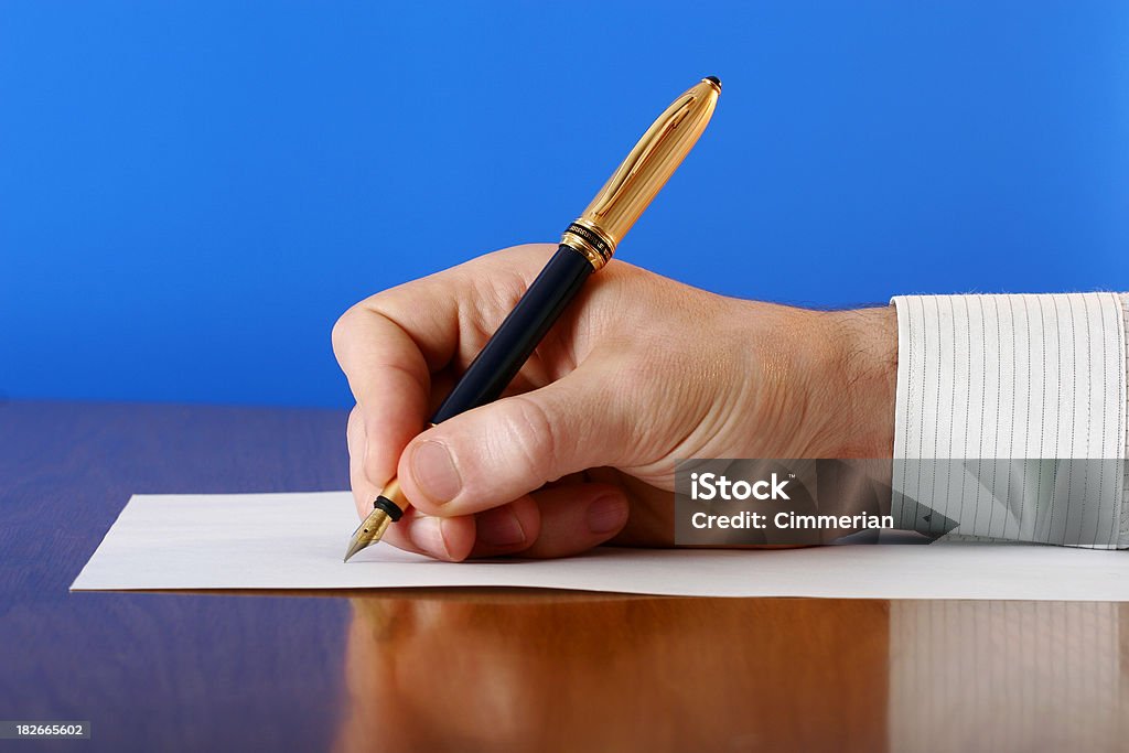 Business notes Close-up of hand with a gilded ink pen writing something on a sheet of paper. Fountain Pen Stock Photo