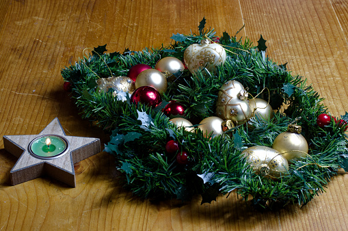 Decoration for Advent and Christmas: various balls between garlands made of conifer branches a burning candle