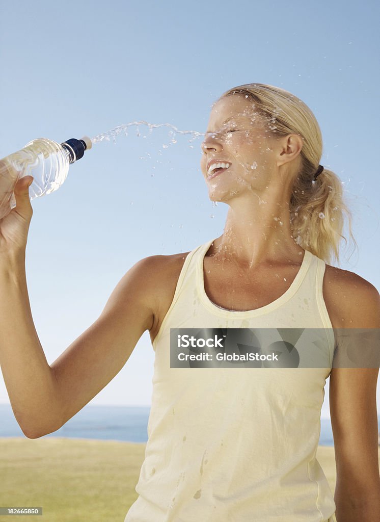 Happy female throwing water on her face to cool off Happy young female throwing water on her face to cool off 20-29 Years Stock Photo