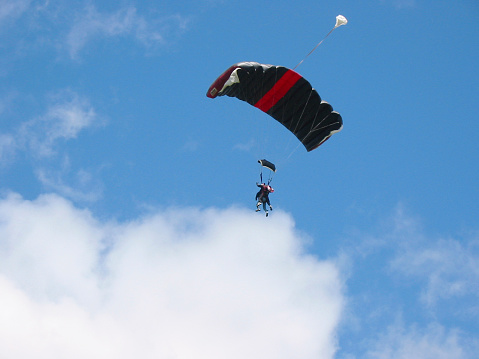 tandem skydivers drifting towards clouds.