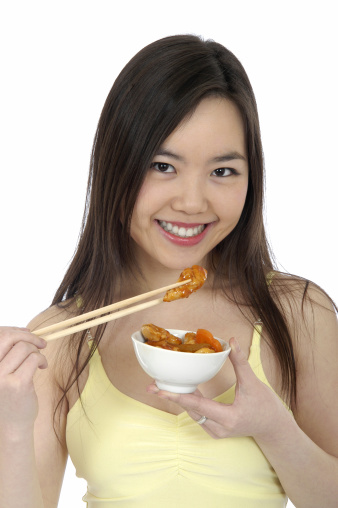 Happy Young woman eating with Chop Sticks