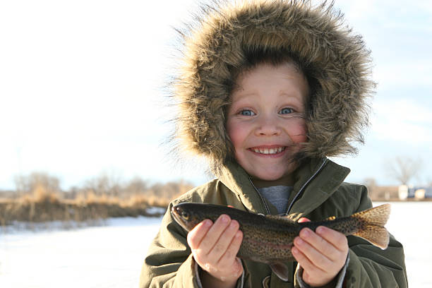 Niño pesca sobre hielo con capacidad de su pescado - foto de stock
