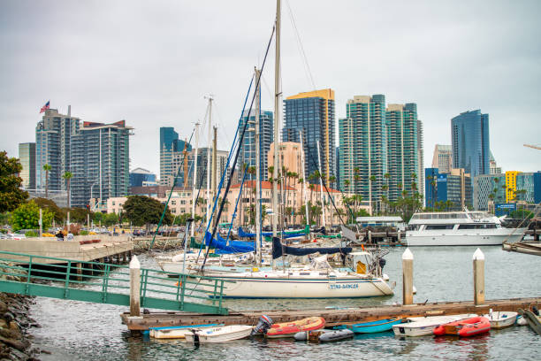 San Diego, California - April 16, 2024: Sailboat on clear blue waters with other boats and cityscape in background.