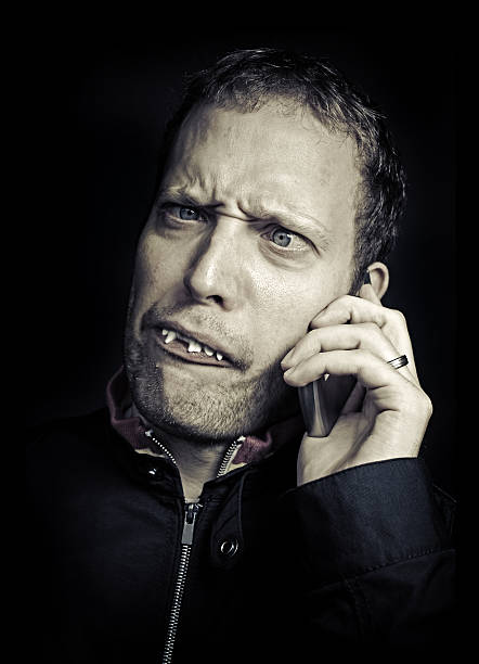 молодой человек с зубы retard на телефоне - ca02 стоковые фото и изображения
