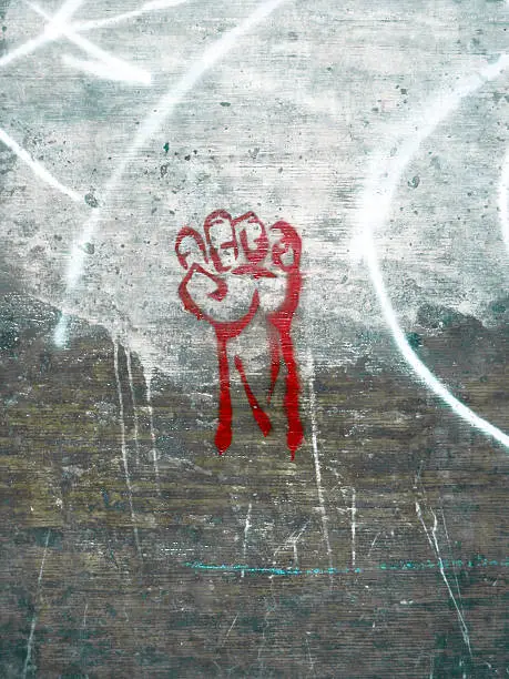 Raised red fist spraypainted on a concrete wall.