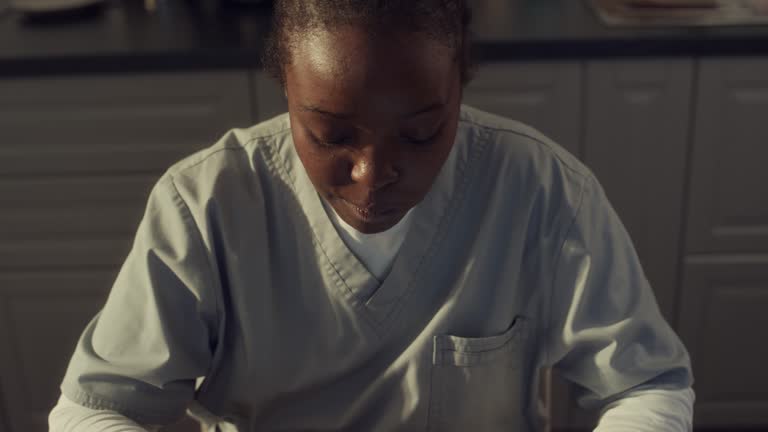 Black Nurse Eating Sandwich with Coffee while Using Smartphone