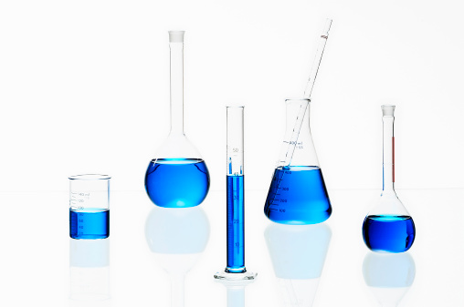 Laboratory glassware filled with blue liquid shot on white background