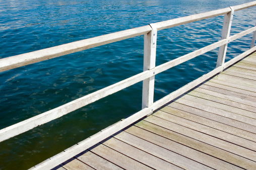 A wooden pier with white railing on he coast