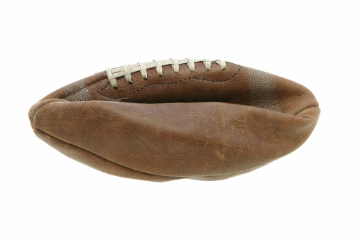 Flat old leather football, ball shows wear and tear.