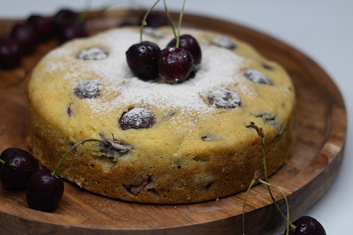 Cherry yogurt cake. Delicious yoghurt cake topped with fresh cherries, a moist and fruity dessert perfect for any occasion. Closeup shot on white background to capture the vibrant colors