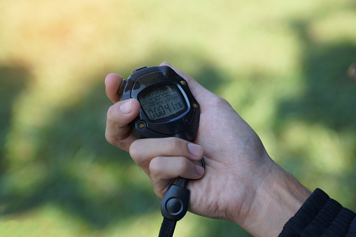 Coach holds a stopwatch to check the runners' speed statistics during practice. soft and selective focus.