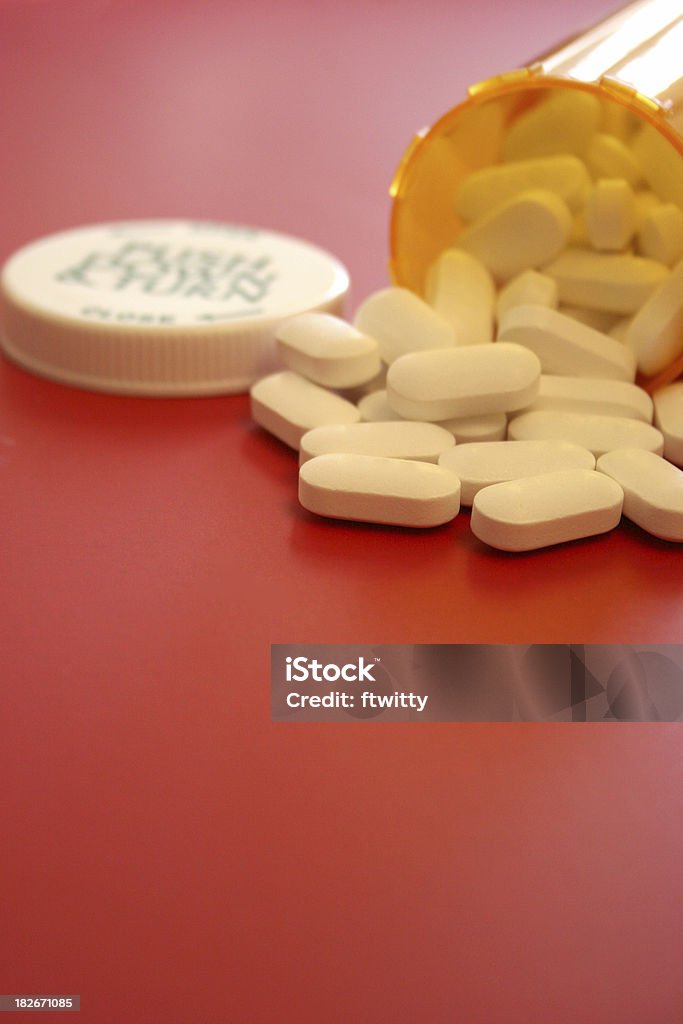 Flacone di pillole su rosso verticale - Foto stock royalty-free di Abbondanza