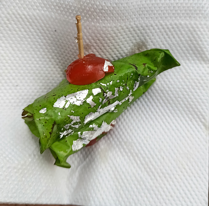 A closeup picture of an Indian Sweet Paan with cherry on top. It is a Betel nut Leaf with areca usually chewed after lunch.