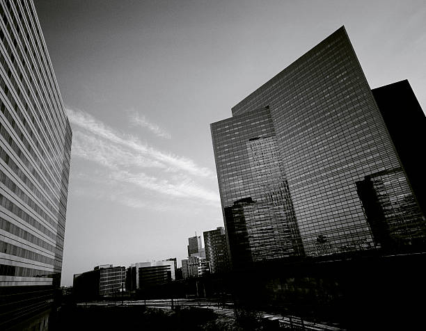 Modern glass architecture reflecting the city of london in monochrome, captured on 35mm film with visible grain, showcases urban development and architectural design